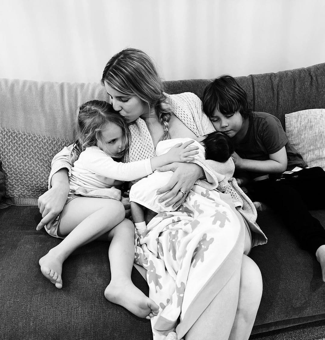 Jessica Urlichs holding newborn with two older children on couch